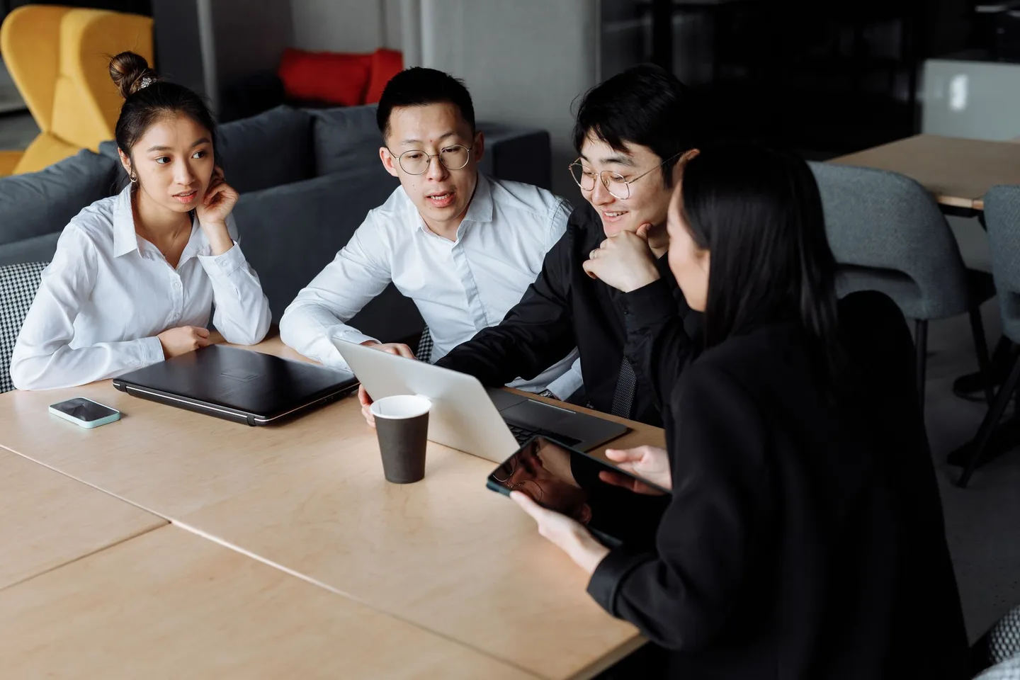 Colleagues discussing a project around a laptop